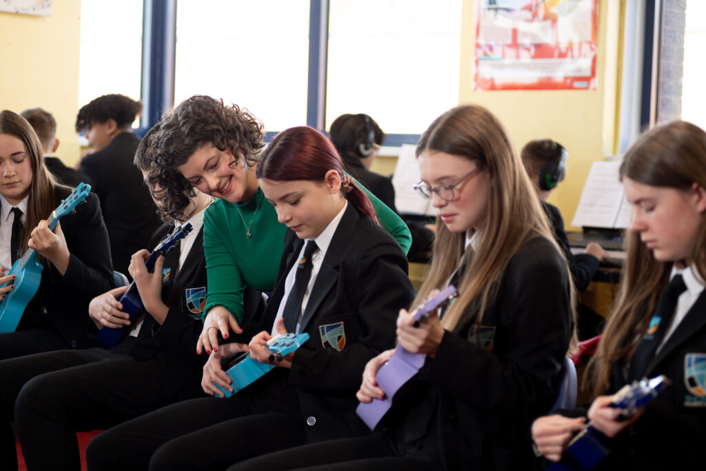A group of students learning to play an instrument with the teachers help